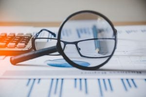 a magnifying glass looking at glasses with information and reports underneath them