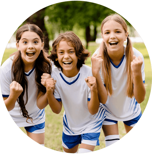 Three children in sports kit, standing together and cheering