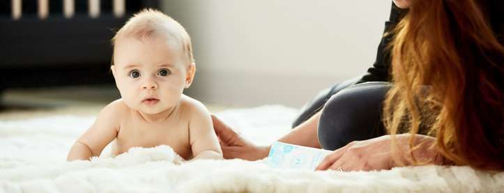 Baby crawling on fluffy rug with mother